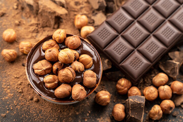 chocolate bar with hazelnuts, handmade sweets. Composition of bars dark chocolates hazelnuts on a black background, top view. Pastry craft on the table for chocolate background