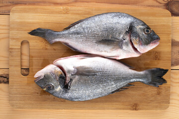 Fototapeta premium Two fresh sea fish Dorado on a bamboo cutting board, close-up, top view