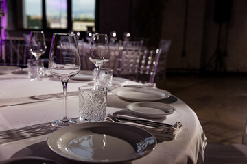 stylish empty glasses and plates at setting at elegant table for wedding reception, catering in restaurant