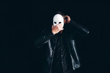Handsome Strong Man Hides Behind a Mask in the Dark Background