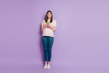 Fototapeta na wymiar Portrait of curious interested funny blogger lady hold cellphone look empty space on violet background
