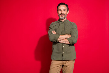 Photo of cool mature man crossed arms wear khaki shirt isolated on red color background