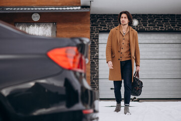 Young handsome business man walking out of the house to his car