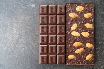 assortment chocolate bars with almonds, handmade sweets. Composition of bars milk and dark almond chocolate on black background, top view. Pastry craft on the table