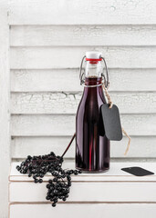 Homemade black elderberry syrup in a small glass bottle. Autumn berry drink concept. Selective...
