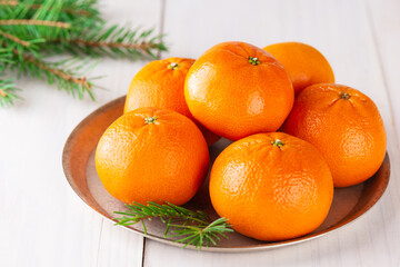 Tangerines with fir branches on a light wooden table. Christmas and New Year concept.