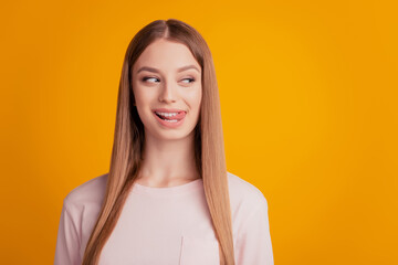 Portrait of flirty dreamy lady show tongue look side empty space cunning face on yellow background