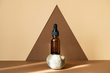 Mock-up of glass dropper bottle stands on stand made of natural stone on abstract geometric...
