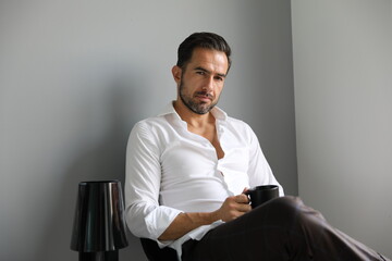 Przystojny brunet w białej koszuli podczas porannej kawy przed wyjściem do pracy. - obrazy, fototapety, plakaty
