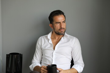 Fototapeta Przystojny brunet w białej koszuli podczas porannej kawy przed wyjściem do pracy. obraz