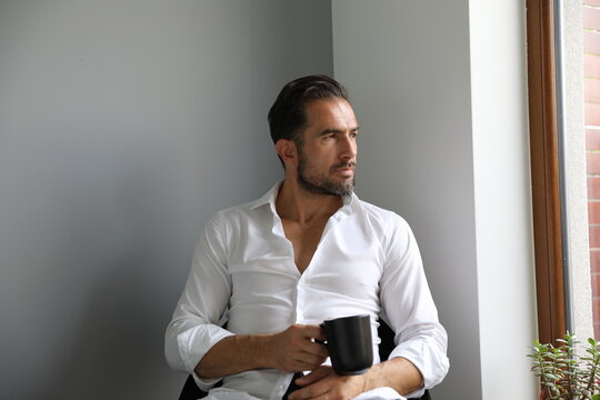 Fototapeta Przystojny brunet w białej koszuli podczas porannej kawy przed wyjściem do pracy.