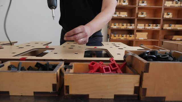 Manufacturing professional die cutter plate - worker hands fastening parts onto plywood plank using screw driver, camera slide