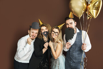 Happy people wearing party hats with photo booth props are celebrating holiday or event