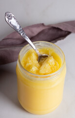 Ghee clarified butter desi in glass jar on a marble background
