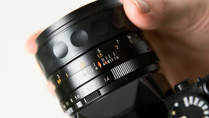 Fototapeta na wymiar Photographer hand changing manual aperture ring on the vintage film photo camera lens.