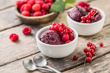 scoop of delicious  ice cream in a contemporary natural situation and lighting. A ball of homemade raspberry walrus with fresh berries  in a white cup on a wooden  background. Close up
