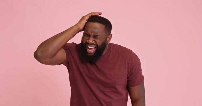 Young African american man scream got headache isolated on pink background