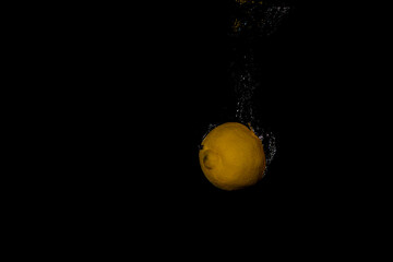 Fototapeta na wymiar Fresh fruit fall into the cold water with air bubbles as symbol for healthy vegan lifestyle in short time exposure of high speed camera