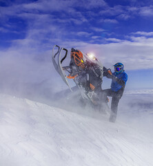 snowmobilers - extreme. the concept of advertising mountain and professional snowmobile driving. a bright pilot and a beautiful jump with a turn on a snowmobile