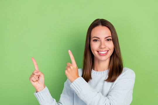 Photo of sweet young brunette lady point empty space wear blue sweater isolated on green color background
