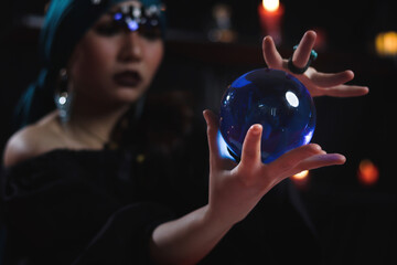 Crystal ball in hand of mysterious magnificent beautiful woman fortune teller in black dress, dark...