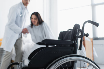 Fototapeta na wymiar modern wheelchair near doctor with patient on blurred background