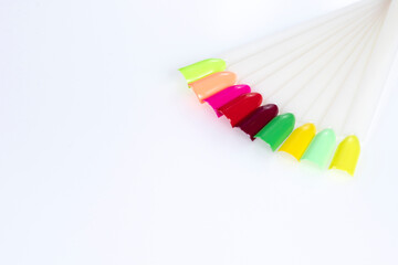 Fototapeta premium Multiсolor nail tips on a white background. examples of manicure for nails. Palette with color samples of nail. Copy space