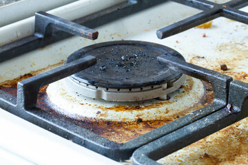 Dirty gas stove surface. Large gas burner and cast iron grate of a gas oven surrounded by old...