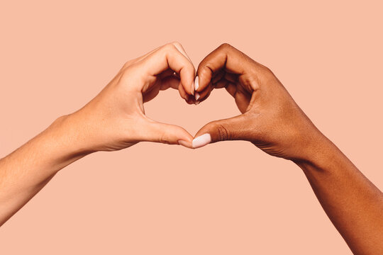 Close up of black and white female hands in heart shape, interracial friendship.