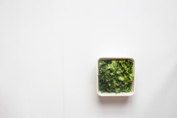 Chopped Fresh Coriander leaves in white plate on white background. top view.