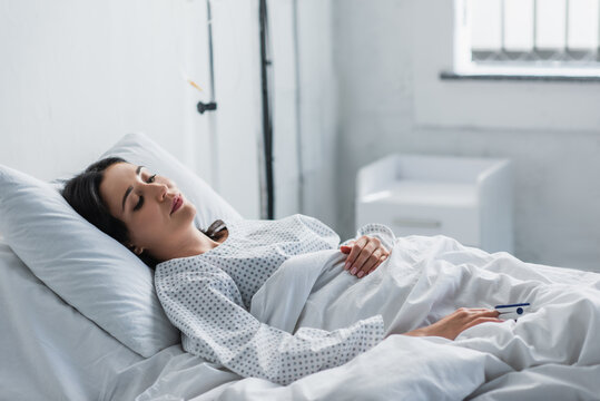 woman in patient gown lying in hospital bed