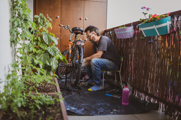 Man fixing his bike on a balcony
