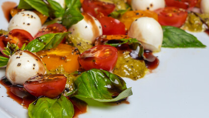 Defocused background of caprese salad. Healthy meal with cherry tomatoes, mozzarella balls, spices and basil.