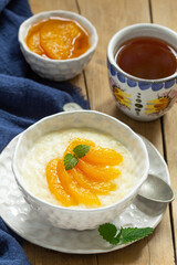 Breakfast of rice porridge with peach jam and tea. Rustic style.