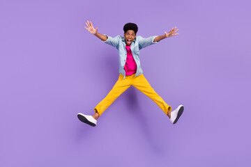 Fototapeta na wymiar Photo of inspired crazy guy jump raise hands open mouth wear blue shirt pants shoes isolated purple color background