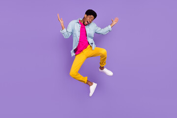 Fototapeta na wymiar Photo of foolish clueless afro guy jump raise hands wear blue shirt pants footwear isolated violet color background