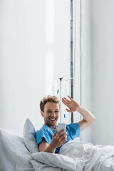 happy patient waving hand while having video call on smartphone in hospital