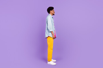 Fototapeta na wymiar Photo of pretty adorable dark skin guy dressed jeans shirt looking empty space smiling isolated violet color background