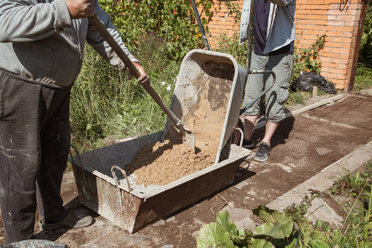 Eldery man kneads cement for pouring a garden path, garden construction work
