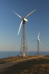Wind generators on the mountain hill at sunset. Renewable energy source. Wind power plant. Cape Meganom, Crimea.