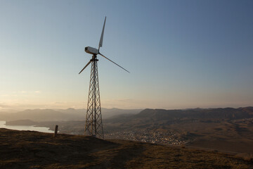 Single wind turbine on the mountain hill at sunset. Renewable source of energy. Green energy generation. Cape Meganom, Crimea.