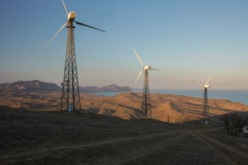 Wind power plant at sunset. Alternative energy source. Wind turbines farm. Cape Meganom, Crimea.