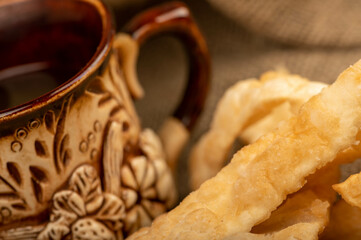 Fried bread sticks with salt and a ceramic mug, close-up, selective focus.