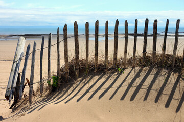 peaceful scene of old wooden fence in sand dunes with beach background