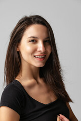 Close-up portrait of young beautiful smiling woman without makeup isolated over gray studio background. Natural beauty concept.