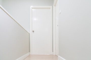 White wall corridor with wooden floor and white door for bedroom.
