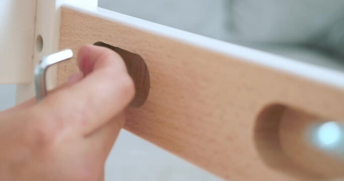 close-up. someone screws a bolt with a screwdriver into a notch on a wooden board