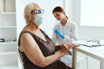 elderly woman wearing a medical mask syringe injection vaccine passport health care