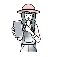 立ってスマートフォンを指差してこちらに向けて見せている農家の女性