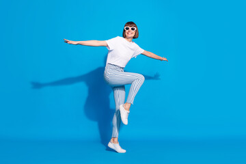 Fototapeta premium Full length body size photo careless girl in sunglass dancing in casual clothes isolated bright blue color background